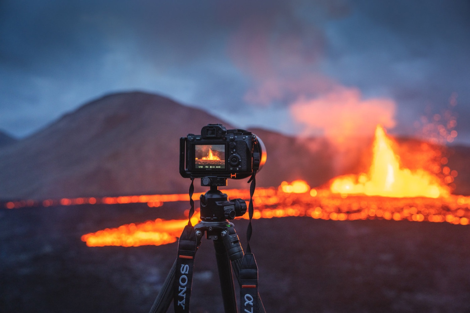Camera on a tripod in front of an erupting volcano